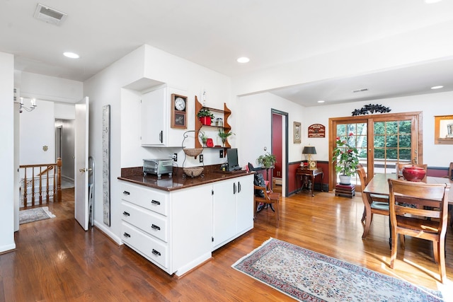 kitchen featuring dark wood-type flooring, kitchen peninsula, and white cabinets