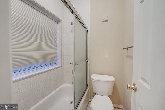 bathroom with combined bath / shower with glass door and toilet