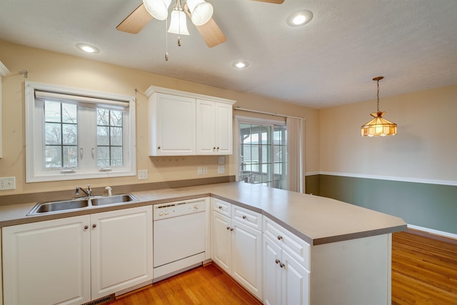 kitchen featuring sink, white cabinetry, white dishwasher, decorative light fixtures, and kitchen peninsula