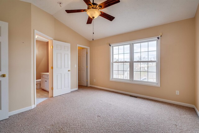 unfurnished bedroom with ceiling fan, lofted ceiling, light colored carpet, and ensuite bath