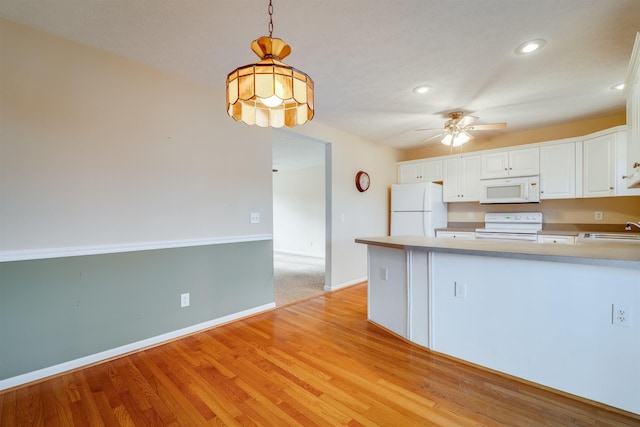 kitchen featuring sink, white appliances, white cabinetry, hanging light fixtures, and kitchen peninsula