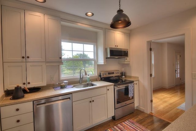 kitchen featuring white cabinets, appliances with stainless steel finishes, light countertops, and a sink