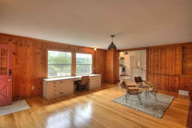 office area with light wood-type flooring, visible vents, and wooden walls