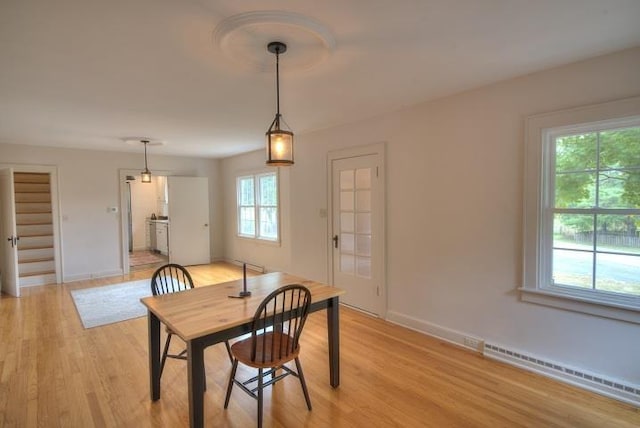 dining area with light wood-style floors, a baseboard radiator, stairs, and baseboards