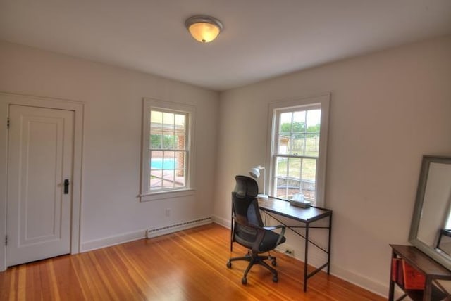 office featuring light wood-type flooring, a wealth of natural light, and baseboard heating