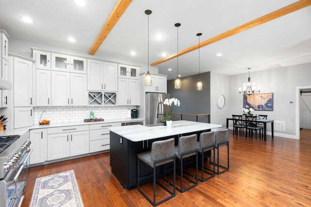 kitchen featuring a breakfast bar, a kitchen island, pendant lighting, stainless steel appliances, and white cabinets