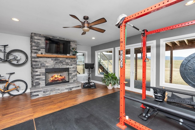 exercise area featuring dark wood-type flooring, ceiling fan, and a fireplace