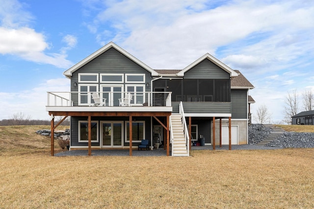 back of property with a deck, a sunroom, and a lawn