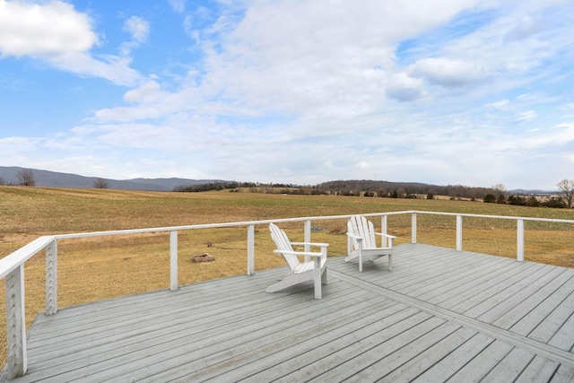 wooden deck featuring an outdoor fire pit, a mountain view, a lawn, and a rural view