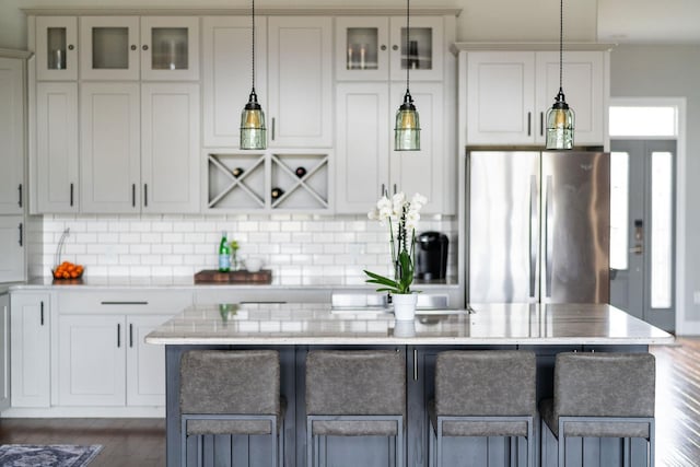 kitchen featuring white cabinetry, decorative light fixtures, stainless steel fridge, and a kitchen island