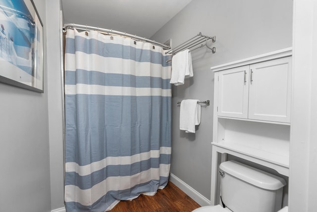 bathroom with hardwood / wood-style flooring, a shower with curtain, and toilet