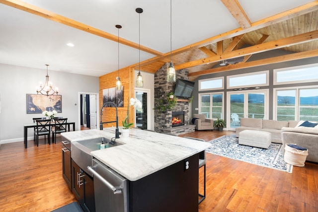 kitchen featuring pendant lighting, light hardwood / wood-style flooring, dishwasher, beam ceiling, and a center island with sink