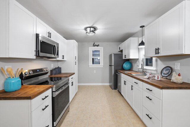 kitchen with wood counters, white cabinetry, and stainless steel appliances