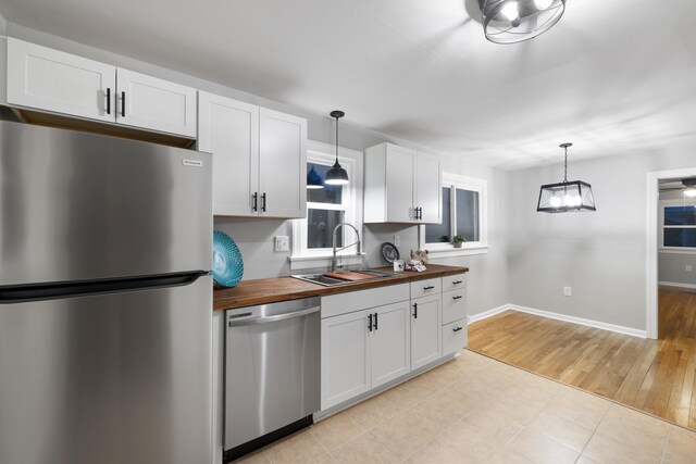 kitchen with pendant lighting, butcher block countertops, stainless steel appliances, and sink