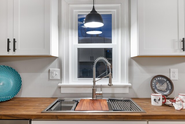 room details with white cabinetry, sink, pendant lighting, and butcher block countertops