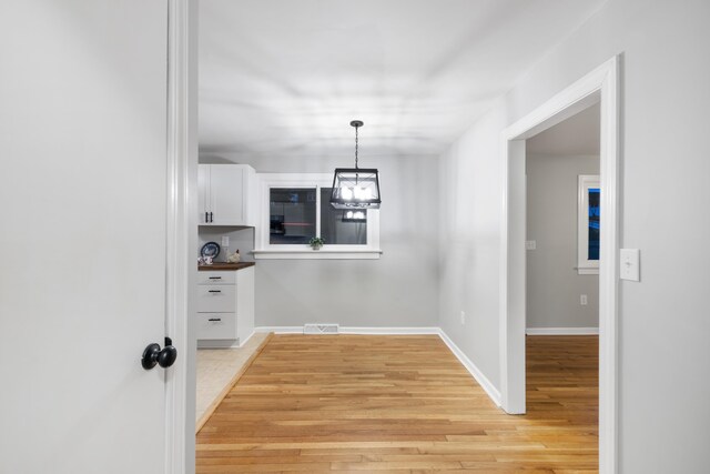 unfurnished dining area with a notable chandelier and light hardwood / wood-style floors