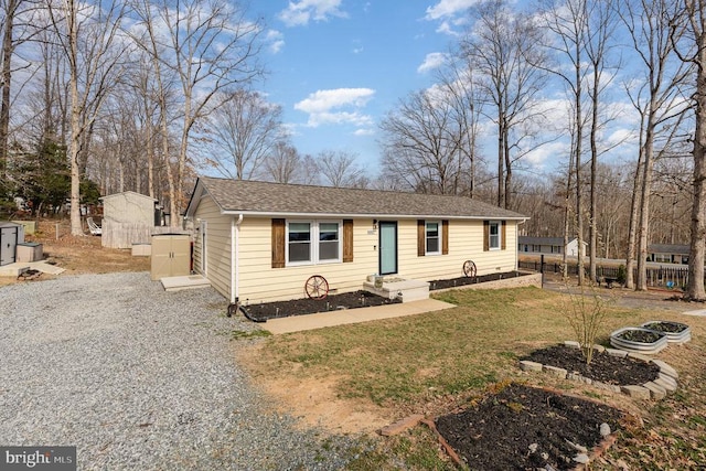 view of front facade featuring a shingled roof, a front yard, and fence