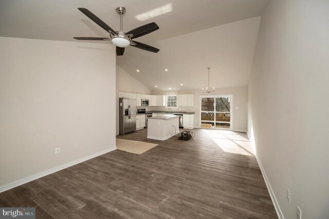 unfurnished living room with ceiling fan with notable chandelier, dark wood-type flooring, and high vaulted ceiling