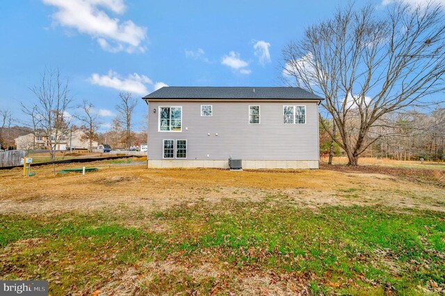 rear view of property with a yard and central air condition unit