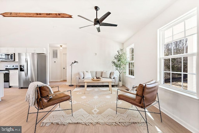 living room with high vaulted ceiling, ceiling fan, baseboards, and light wood-style floors