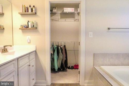 full bath featuring tiled bath, wood finished floors, and vanity