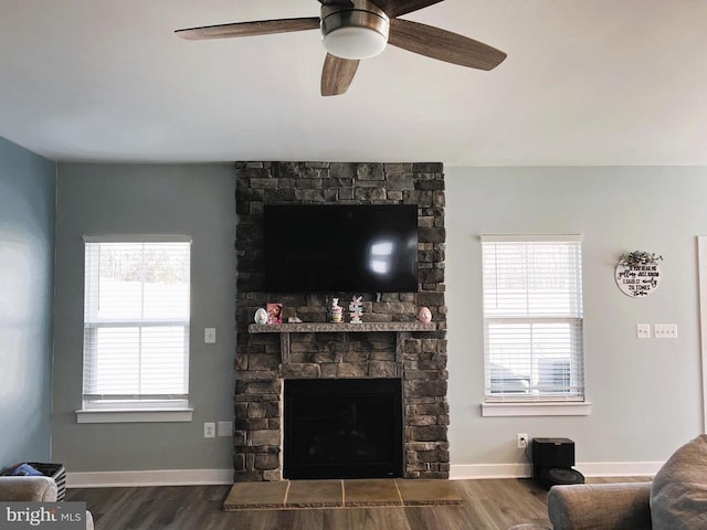 living area with dark wood-type flooring, a fireplace, baseboards, and ceiling fan