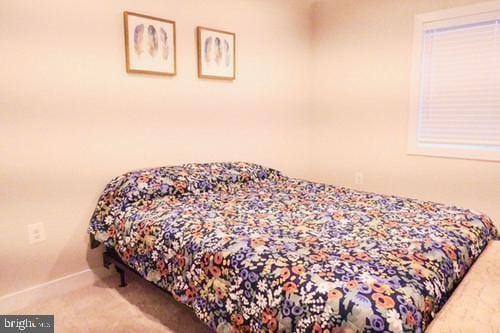 bedroom featuring light colored carpet and baseboards