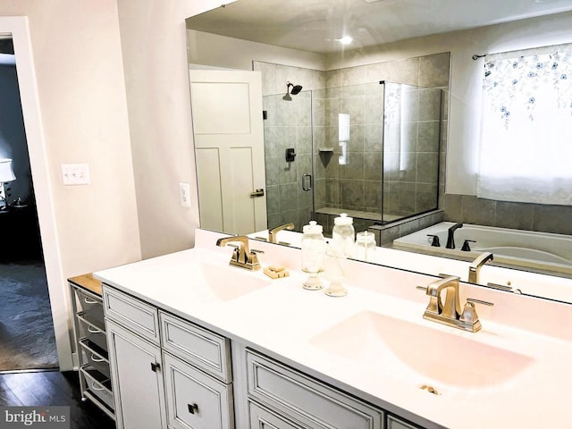 full bathroom featuring a garden tub, wood finished floors, a sink, a shower stall, and double vanity