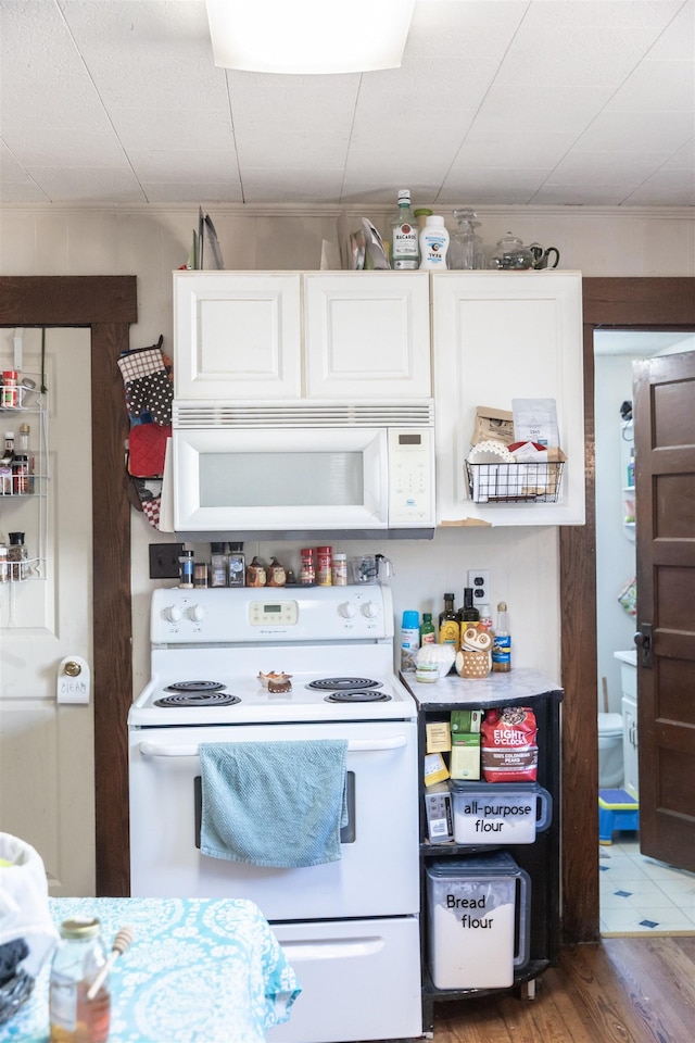 kitchen featuring white appliances, white cabinets, and wood finished floors