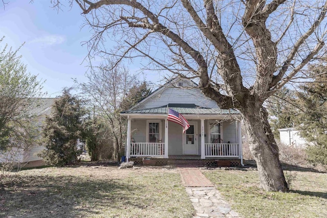 view of front facade featuring covered porch, metal roof, and a front yard