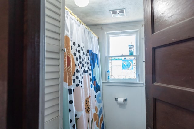 bathroom with visible vents, a textured ceiling, a healthy amount of sunlight, and a shower with curtain