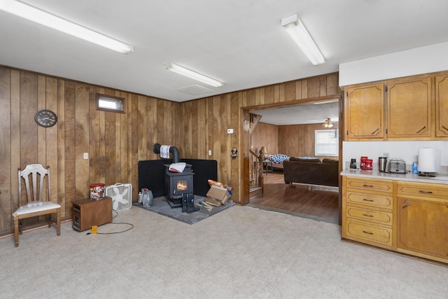 home office featuring a wood stove, wooden walls, visible vents, and light floors