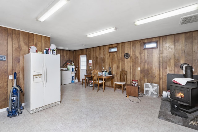 interior space featuring tile patterned floors, wooden walls, plenty of natural light, a wood stove, and washer / dryer