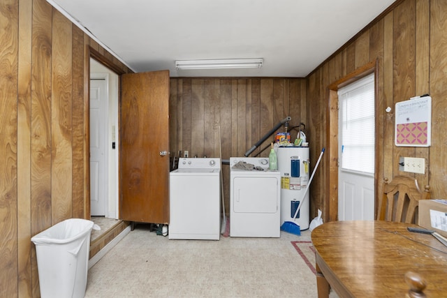 laundry area with laundry area, electric water heater, wood walls, washing machine and dryer, and light floors