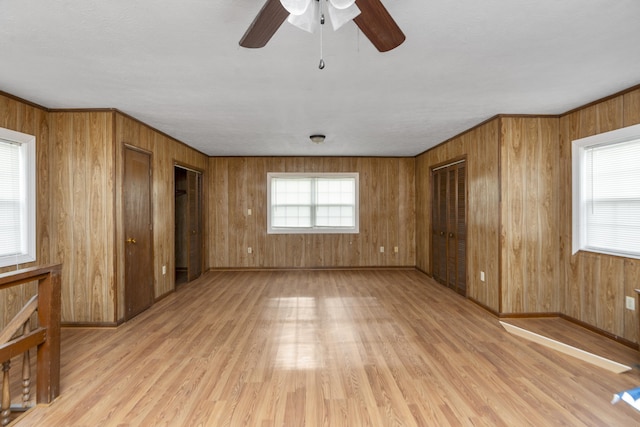 interior space with wood walls, ceiling fan, light wood finished floors, and baseboards
