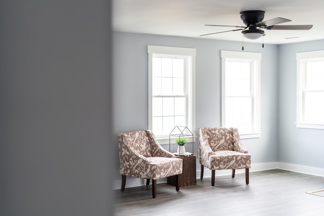 living area featuring ceiling fan, baseboards, and wood finished floors
