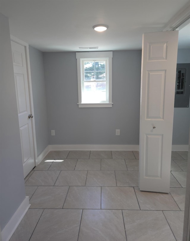 unfurnished room with visible vents, light tile patterned flooring, baseboards, and electric panel