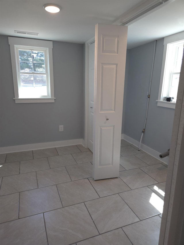 interior space featuring light tile patterned floors, baseboards, and visible vents