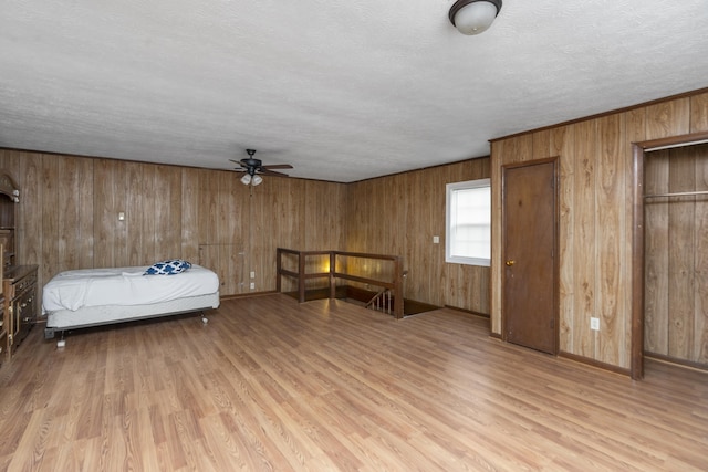 bedroom with wooden walls, a textured ceiling, and wood finished floors