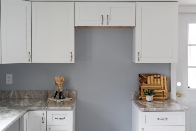 kitchen featuring white cabinets, plenty of natural light, and light stone countertops