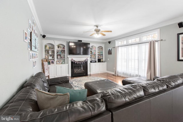 living room featuring ornamental molding, wood-type flooring, ceiling fan, and built in shelves