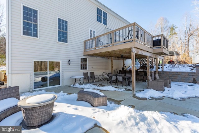 snow covered rear of property with a deck