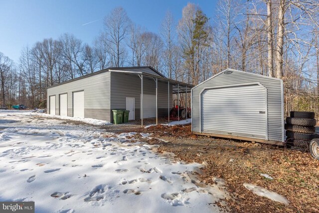 snow covered garage with a carport