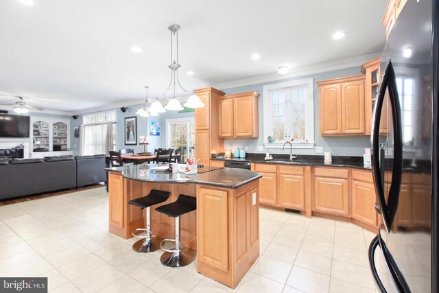 kitchen featuring sink, decorative light fixtures, a center island, ornamental molding, and black appliances