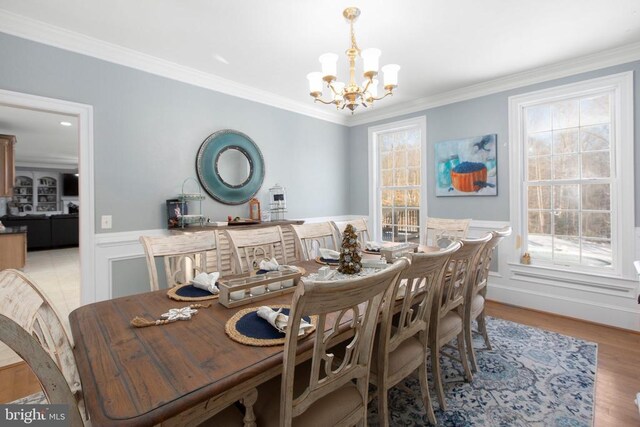 dining space with a notable chandelier, ornamental molding, and light wood-type flooring