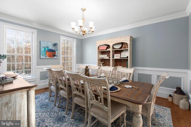 dining room featuring an inviting chandelier, hardwood / wood-style floors, and crown molding