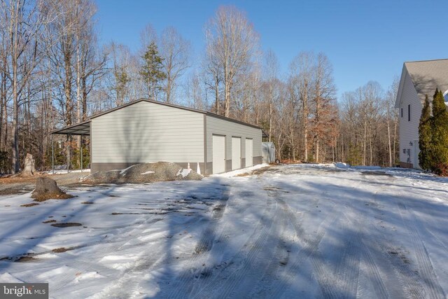 snow covered property with a garage and an outdoor structure