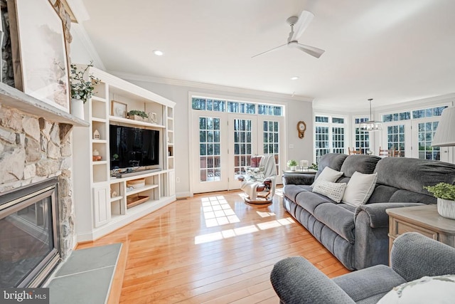 living area with crown molding, light wood-style flooring, a fireplace, and ceiling fan