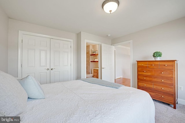 bedroom with a closet, light colored carpet, and ensuite bath