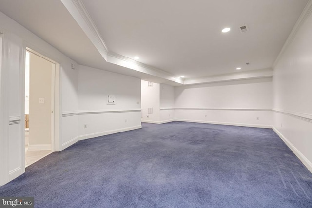 empty room with baseboards, a tray ceiling, recessed lighting, ornamental molding, and dark colored carpet